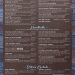 Restaurant menu page 1 featuring three main sections: Appetizers, Handhelds, and Entree Salads. The Appetizers section includes items like Buffalo Wings, Cheese Curds, Bavarian Pretzels, Pickle Fries, and more. The Handhelds section offers various burgers, tacos, sandwiches, and melts, such as The Pla-Mor Burger, The Local Burger, The Danish Blue, and The Hot Chic. The Entree Salads section includes options like The Wedge, Fiesta Bowls, and Simply Caesar. Prices range from $6.00 to $19.00, with additional charges for adding grilled chicken or Adobe grilled shrimp to salads.
