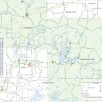 A detailed ATV/UTV trail map of the Cable Area, Wisconsin, highlighting designated routes, trails, and key landmarks. The map includes municipal boundaries, restricted areas, and sponsoring business locations such as lodging, rentals, restaurants, and repair shops. Symbols indicate amenities like fuel stations, public Wi-Fi, EV charging, and apparel shops. Major lakes, highways, and forest roads are labeled, along with ATV clubs and resorts that provide direct trail access. The legend clarifies trail types, access restrictions, and county boundaries.